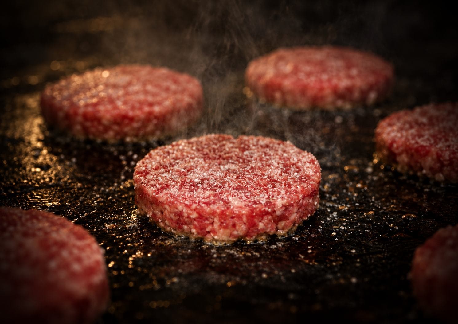 Onestar beef patties cooking on a hot griddle